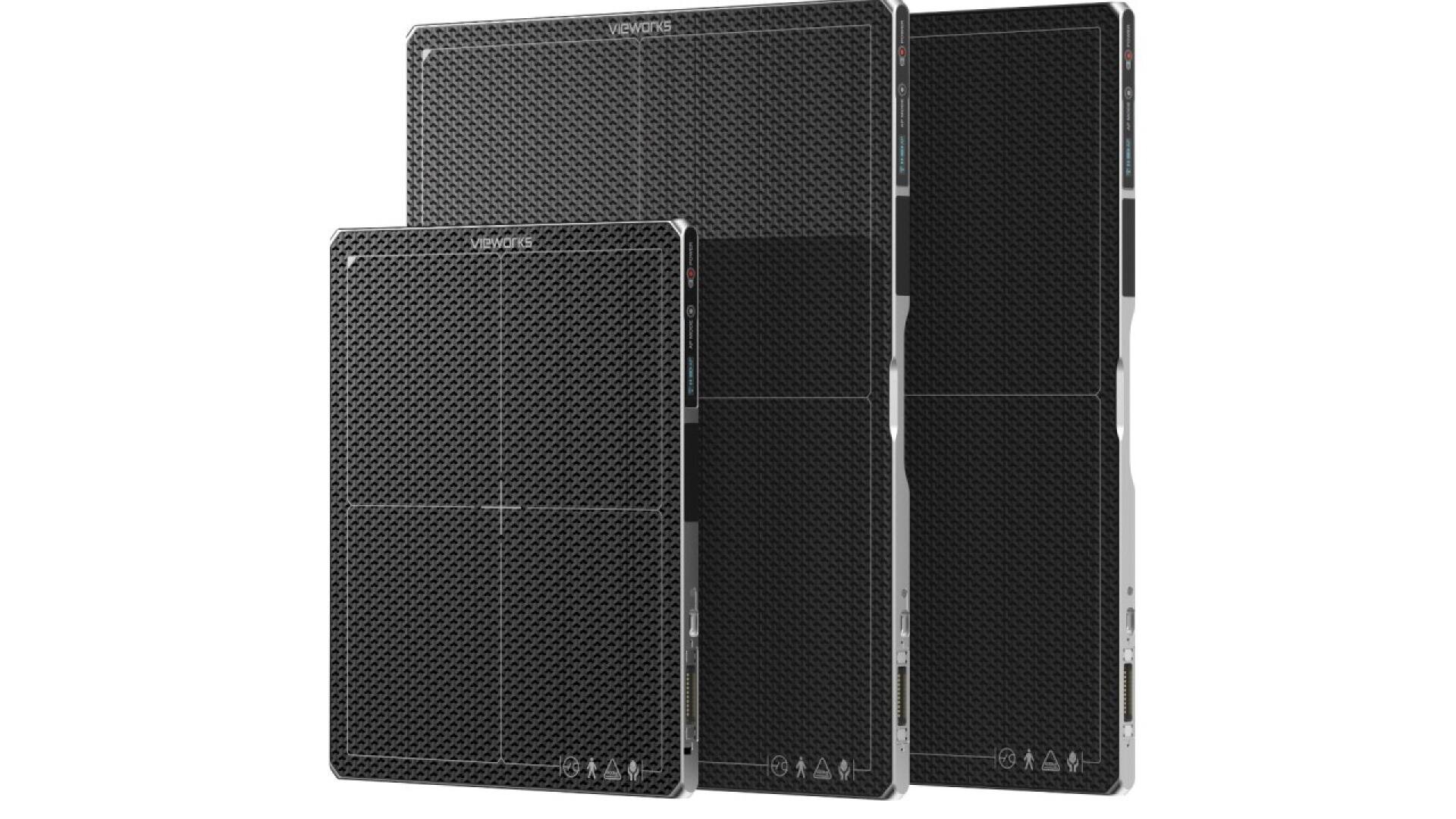 Trois appareils électroniques rectangulaires noirs, aux surfaces texturées et aux bords arrondis, sont représentés debout, de tailles différentes, côte à côte, sur un fond blanc.