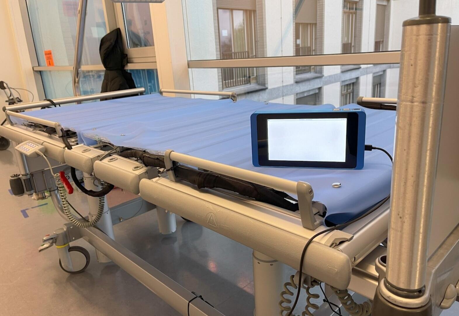 Ein blaues Tablet, dessen Bildschirm ausgeschaltet ist, liegt auf einer Krankentrage.