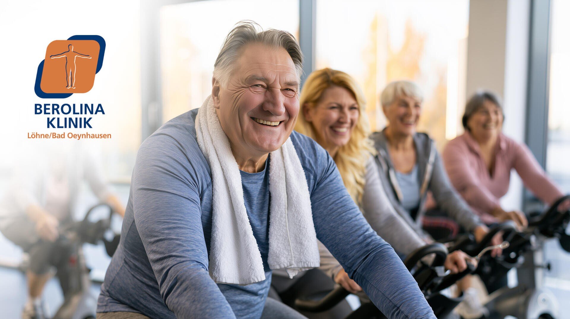 Vier Senioren lächeln, während sie in einem hellen Fitnessraum auf Heimtrainern trainieren. Der Mann im Vordergrund hat ein Handtuch um den Hals. Auf der linken Seite des Bildes ist das Logo der Berolina Klinik zu sehen.