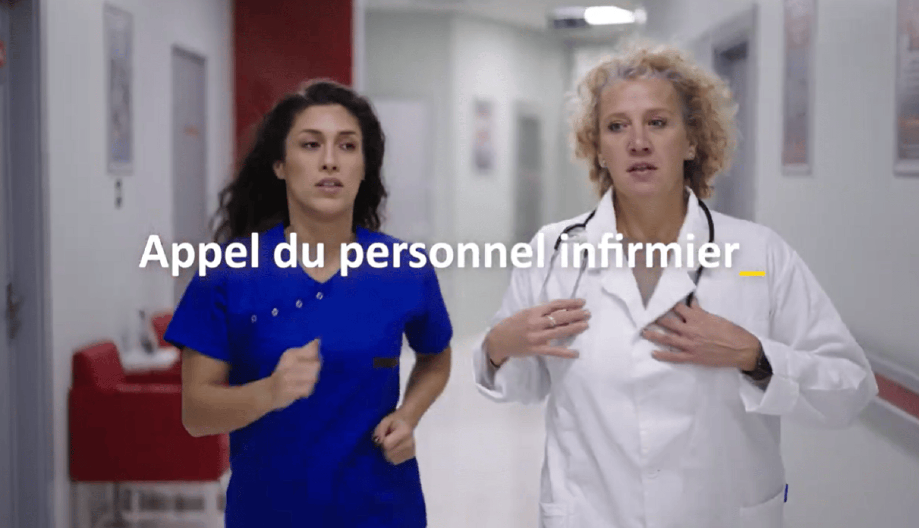 Deux professionnels de la santé, l'un en blouse bleue et l'autre en blouse blanche, marchent rapidement dans un couloir d'hôpital. Le texte français en surimpression indique : "Appel du personnel infirmier".