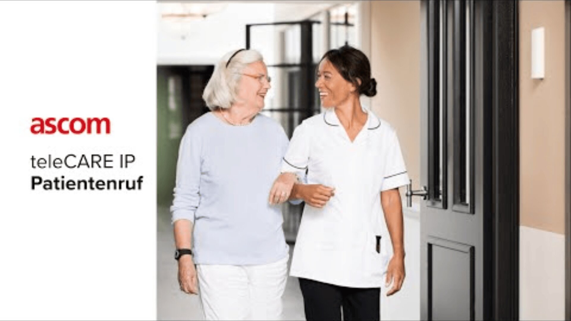 Eine ältere Frau und eine Krankenschwester gehen lächelnd zusammen durch einen Flur. Auf der linken Seite des Bildes steht der Text: ascom teleCARE IP Patientenruf.