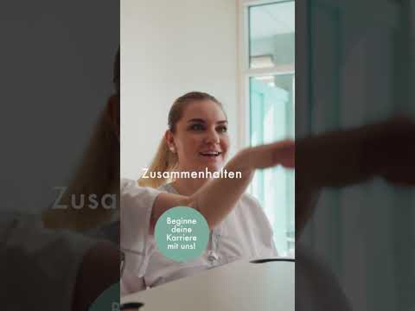 Eine lächelnde Frau in einem weißen Kittel sitzt an einem Tisch und gestikuliert. Der deutsche Text lautet: „Zusammenhalten“ und „Beginne deine Karriere mit uns!“. Im Hintergrund sind große Fenster zu sehen.