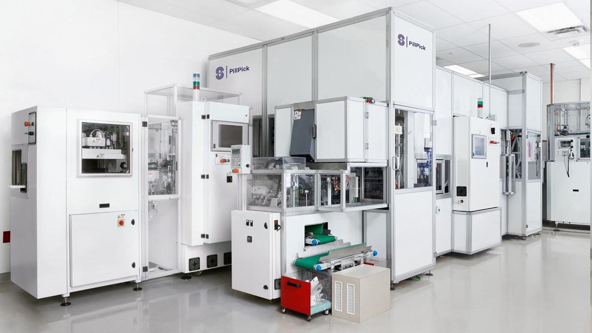Eine Reihe moderner, weißer Laborautomaten in einem sauberen, hell erleuchteten Labor mit glänzenden Böden und geordneten Geräten.