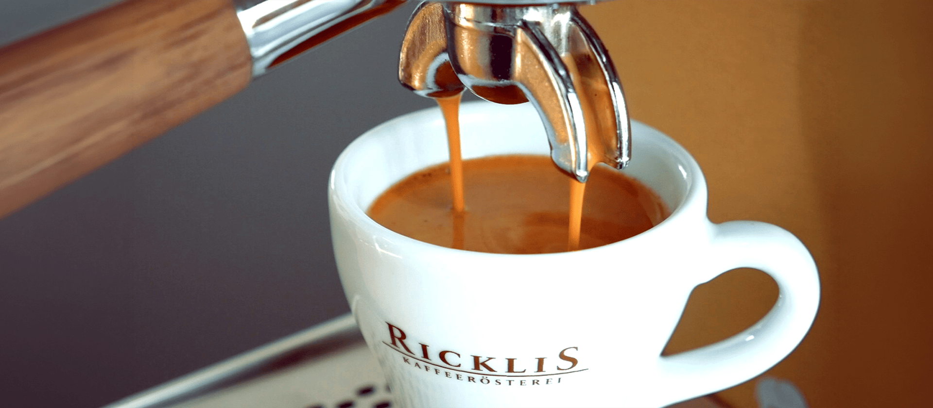 Espresso fließt aus einer Kaffeemaschine in eine weiße Tasse der Ricklis Kaffeerösterei und bildet dabei eine glatte Crema-Schicht auf der Oberfläche.