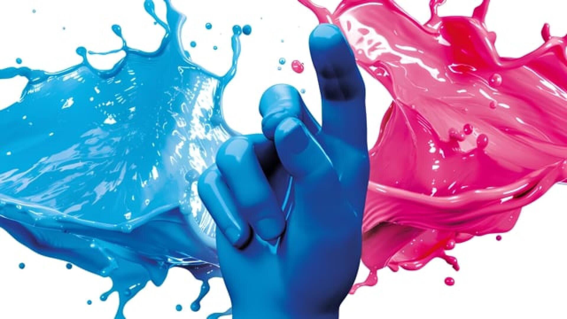 Eine blau bemalte Hand, die zwischen blauen und rosa Farbspritzern nach oben zeigt.