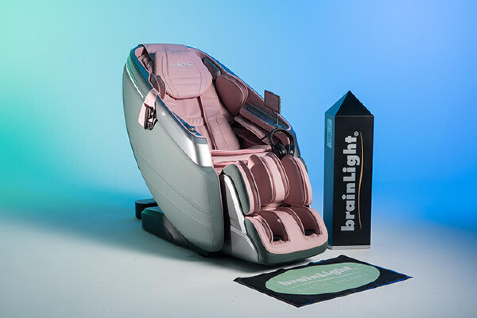 Un fauteuil de massage gris et rose, à côté d'un pilier et d'un tapis de sol de la marque BrainLight.