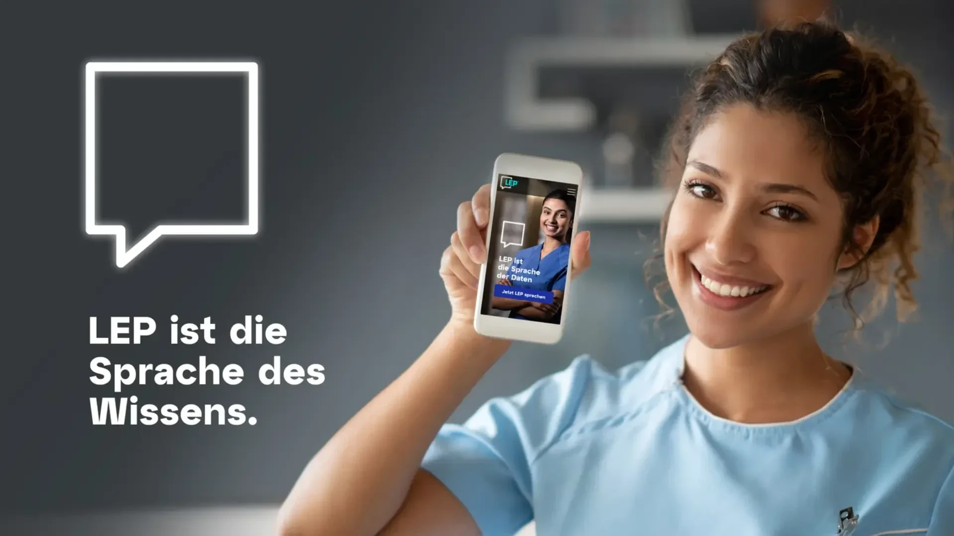 Eine lächelnde Frau in hellblauem Kittel hält ein Smartphone hoch, auf dem ihr Bild zu sehen ist. Neben ihr steht auf Deutsch LEP ist die Sprache des Wissens. und ein Sprechblasensymbol ist auf grauem Hintergrund zu sehen.