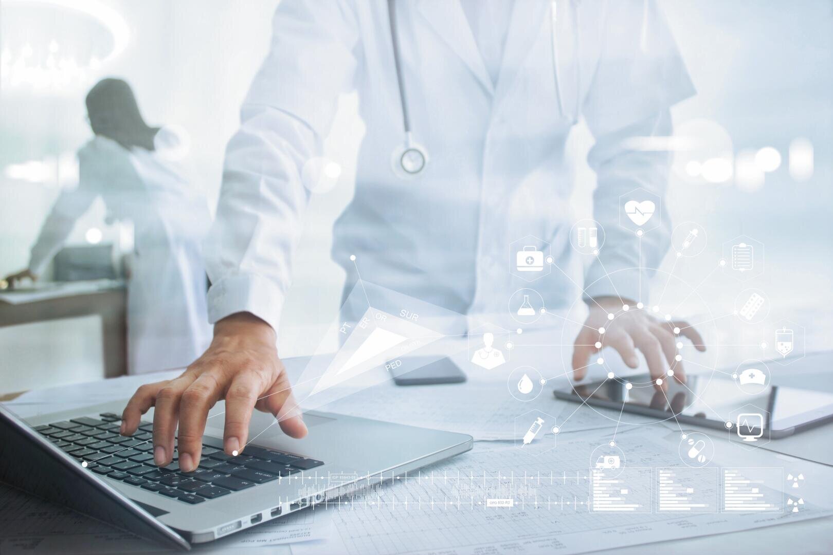 Ein Arzt in einem weißen Kittel benutzt einen Laptop und schreibt an einem Schreibtisch auf Papier, wobei medizinische Symbole und Datengrafiken eingeblendet werden, was auf eine digitale Gesundheitsversorgung oder Telemedizin hindeutet. Eine weitere Person ist unscharf im Hintergrund zu erkennen.